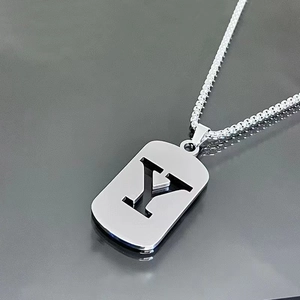 Macro shot of silver letter Y pendant in rectangular military tag style with steel chain