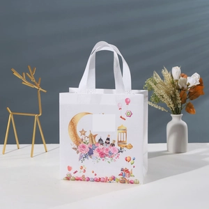 White non-woven gift bag with golden crescent moon and floral patterns for Eid celebrations