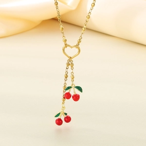 Detail of gold bead chain necklace with red enamel cherry pendants on silk background