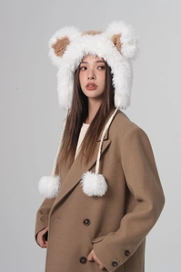 Detail view of plush bear-eared bucket hat with soft fur balls and braided ties