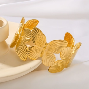 Elegant 18K gold butterfly bangle for women on a ceramic decor with silk background