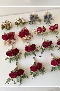 Close-up of handmade wedding corsages with red roses and dried eucalyptus leaves