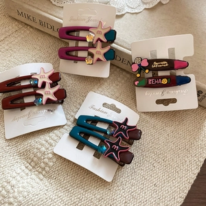 Detail of colorful resin starfish hair clips in wine red and green on display card