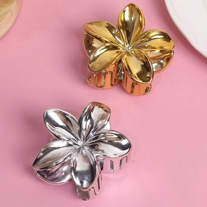 Minimalist gold and silver flower hair claw clips with metallic finish on pink background