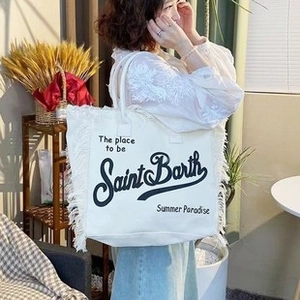 Close-up of white canvas beach tote featuring side tassels and black summer lettering