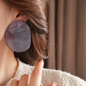 Close-up of purple circular resin earrings with unique texture worn by a female model