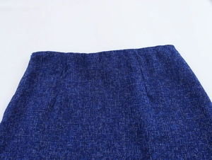 Detailed macro view of dark blue tweed fabric texture and waistband on the skirt