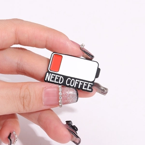 Creative battery-shaped enamel pin featuring NEED COFFEE text and low battery icon