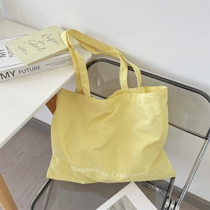 Detail of a bright yellow canvas tote bag with white French print on a stylish chair