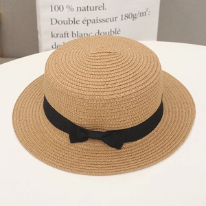 Detail of light brown straw beach hat featuring an elegant black ribbon bow decoration