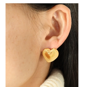 Macro detail of gold heart earrings featuring elegant pleated textures on tarnish-free steel