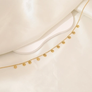 Detailed view of golden Tree of Life charms on a link chain draped over white silk