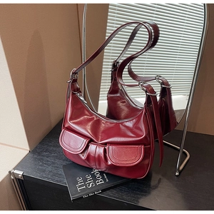 Detail of dark red glossy leather shoulder bag with decorative double flap pockets