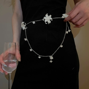 Detail of silver chain belt with white pearl-centered flowers on a black dress