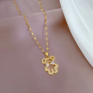 Macro shot of gold-plated bear pendant with sparkling crystals and bow detail on fine chain