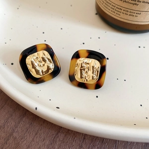 Close-up of square tortoiseshell acetate earrings with hammered 18k gold-plated metal