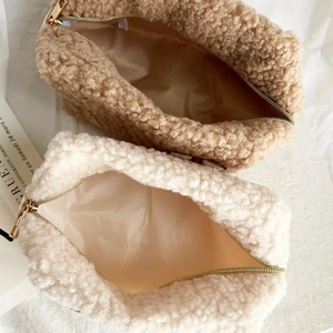 Draufsicht auf zwei Lammwolle-Kosmetiktaschen in Beige und Khaki mit Goldreißverschluss