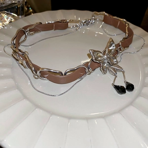 Detail of a brown leather necklace featuring a crystal butterfly pendant with black beads