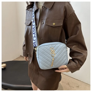 Detail of light blue V-quilted crossbody bag with tassel and floral patterned strap
