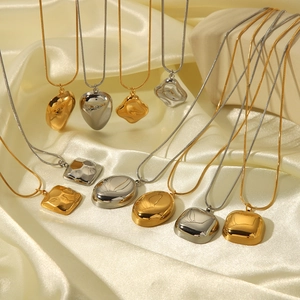 Minimalist 18K gold and silver geometric necklaces on elegant beige silk fabric background