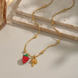 Detail of 18K gold chain necklace with red strawberry and spotted mushroom charms