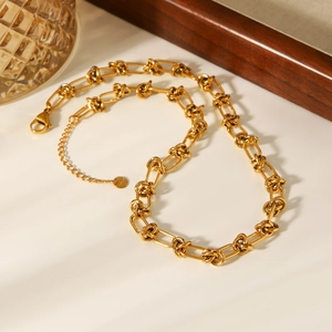18K gold plated stainless steel knot chain necklace on a minimalist beige background