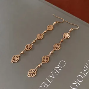 Vintage gold hollow clover drop earrings elegantly placed on a classic grey book cover