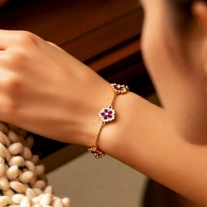 Close-up of a delicate 18k gold-plated flower bracelet on a female wrist in a warm setting