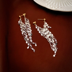 Elegant gold and silver long tassel earrings with sparkling sequins on brown silk