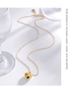 Detail of gold plated heart pendant necklace with high luster finish on white background