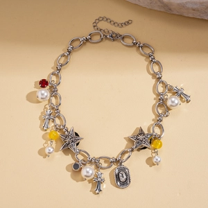 Close-up of vintage silver necklace with cross, star, and pearl charms on stone