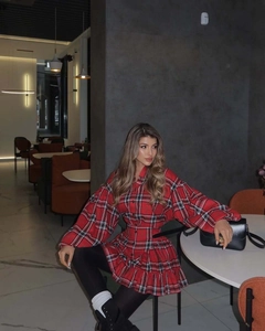 Detail of red plaid dress showing lantern sleeves and waist design in a modern setting