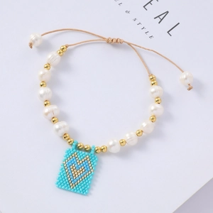 Detail of bohemian pearl bracelet featuring a light blue woven heart charm and gold beads