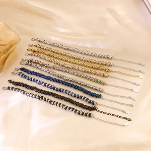Close-up of twisted metal chain bracelets in gold, silver and rainbow stainless steel