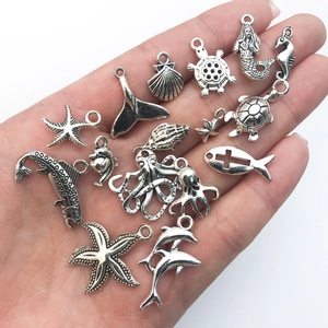 Detalle de dijes marinos de plata antigua con estrella de mar y tortuga para joyería artesanal