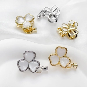 Gold and silver clover jewelry clasps with mother-of-pearl inlay on white fabric