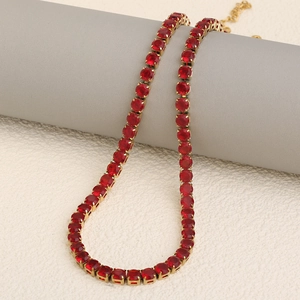 18K gold plated tennis necklace with vibrant red zircon stones on a gray pedestal