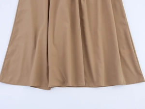 Detailed view of khaki pleated dress hem featuring smooth drapes and premium fabric texture