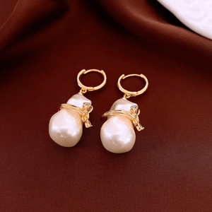 Close-up of golden bow earrings with baroque pearls and sparkling zircon details