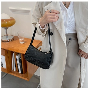 French style black pleated shoulder bag with wavy texture on a model in an indoor setting