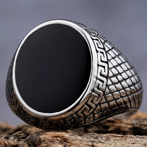 Detailed macro view of vintage men's ring with black oval stone and Greek key engraving