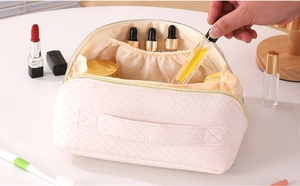Detail of beige woven makeup bag with interior compartments and hand holding perfume