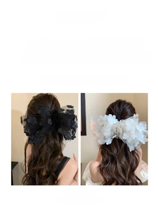 Detail view of large mesh bow hair clip with 3D floral accents in black and white