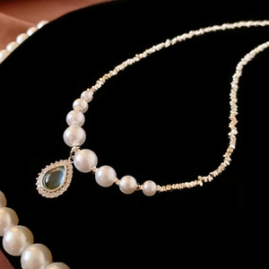 Vintage silver-tone pearl necklace with a teardrop turquoise pendant on black velvet
