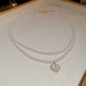 Detail showing double-layer pearl necklace with a radiant heart pendant on a display tray