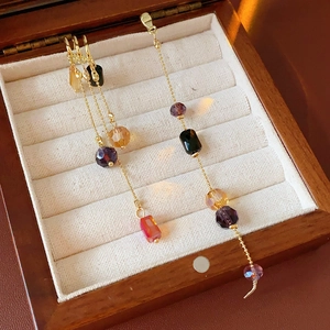 Detail view of gold tassels with purple, amber, and red faceted beads in a jewelry box