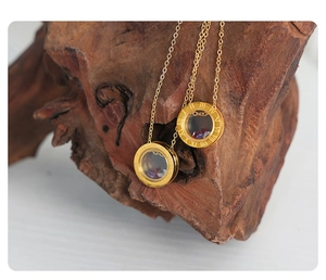 Close-up of golden titanium necklaces with Roman numeral charms and colored stones on wood