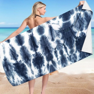 Blue and white tie-dye microfiber beach towel with quick-dry texture on beach background