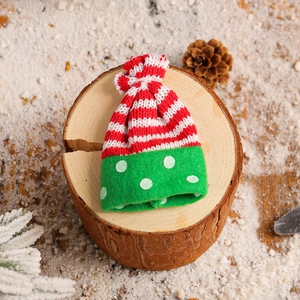 Mini knitted snowman wine bottle cover with red stripes and green polka dots on wood