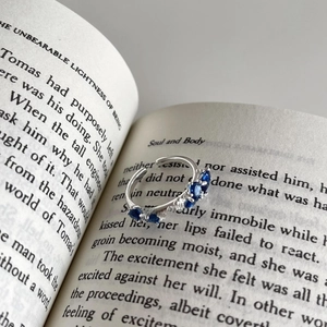 Detail of 925 sterling silver open ring featuring five blue oval gemstones in prong setting